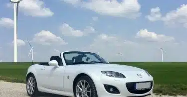 white porsche 911 on green grass field under blue sky during daytime