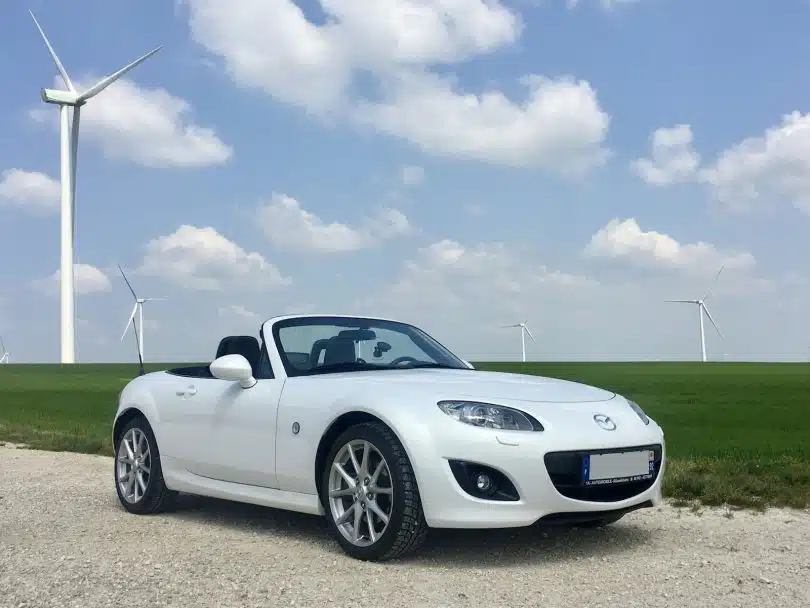 white porsche 911 on green grass field under blue sky during daytime