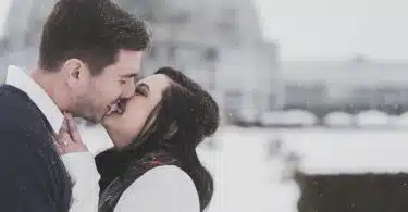 man and woman kissing in snow weather